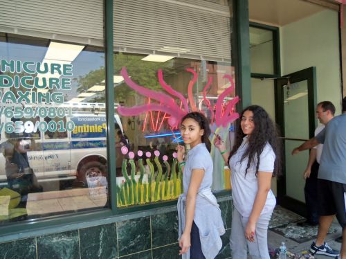 students painting windows on Central Avenue shop for City of Trees initiative