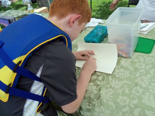 Child drawing frogs under the Frogs Are Green tent at The City of Water event in Hoboken.