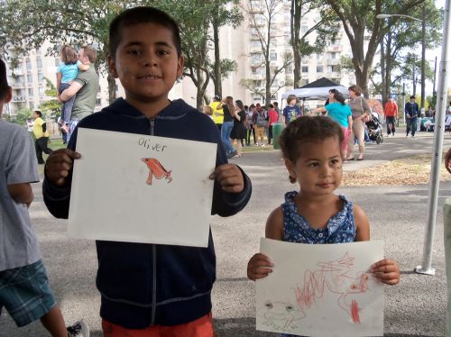Children pose with their frog art in the Frogs Are Green tent at WPLIVE